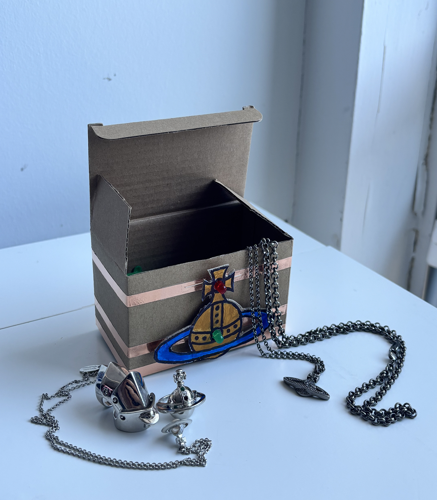 Here lies my collection of Vivienne Westwood jewelry. Since the pieces are made of brass and/or recycled silver (925), they’re conductive and can light up an LED when touched. The whole box is taped using the parallel circuit method, with the button carefully situated at the bottom.